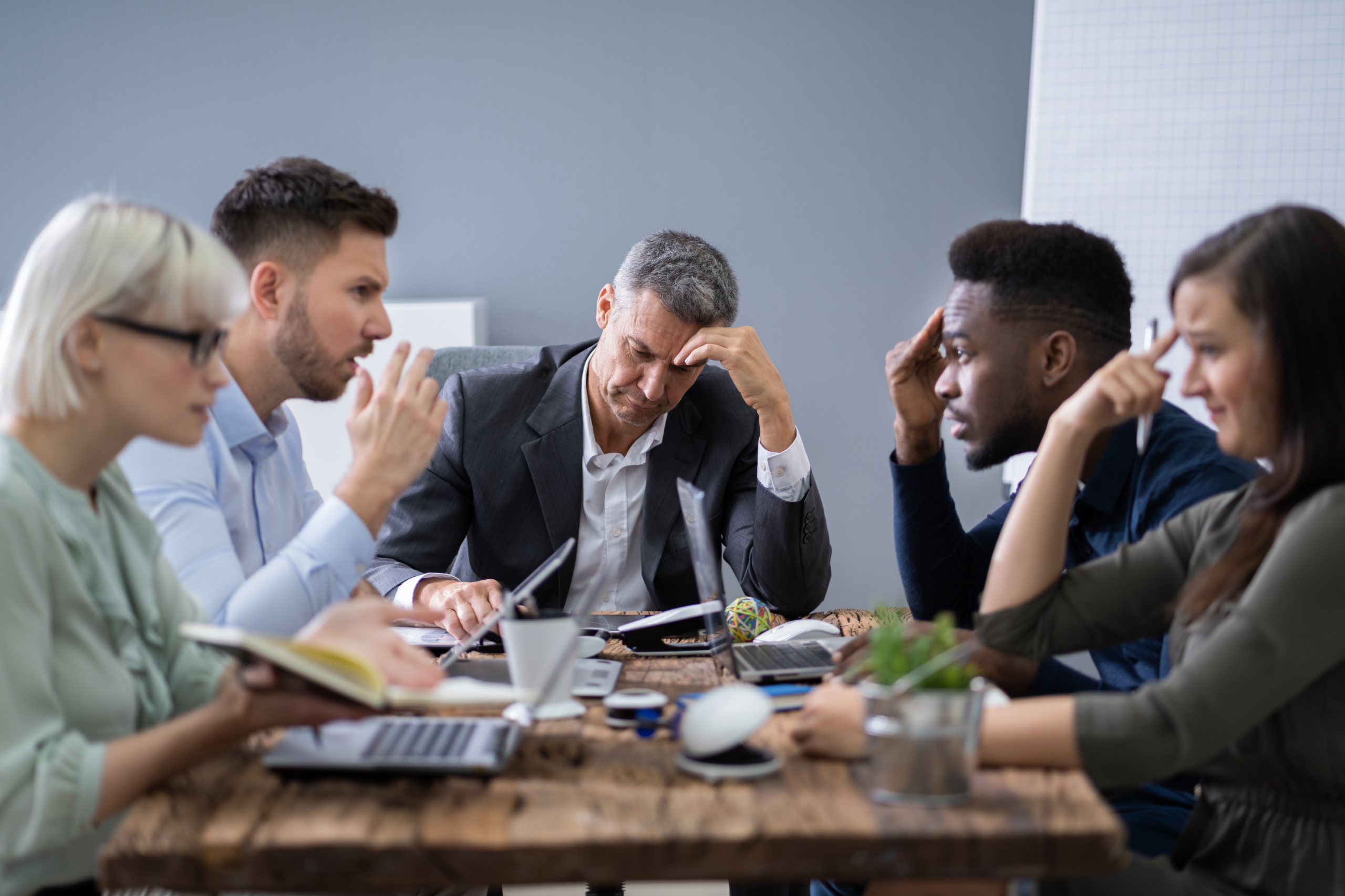 People arguing around a table in the workplace; conflict at work.